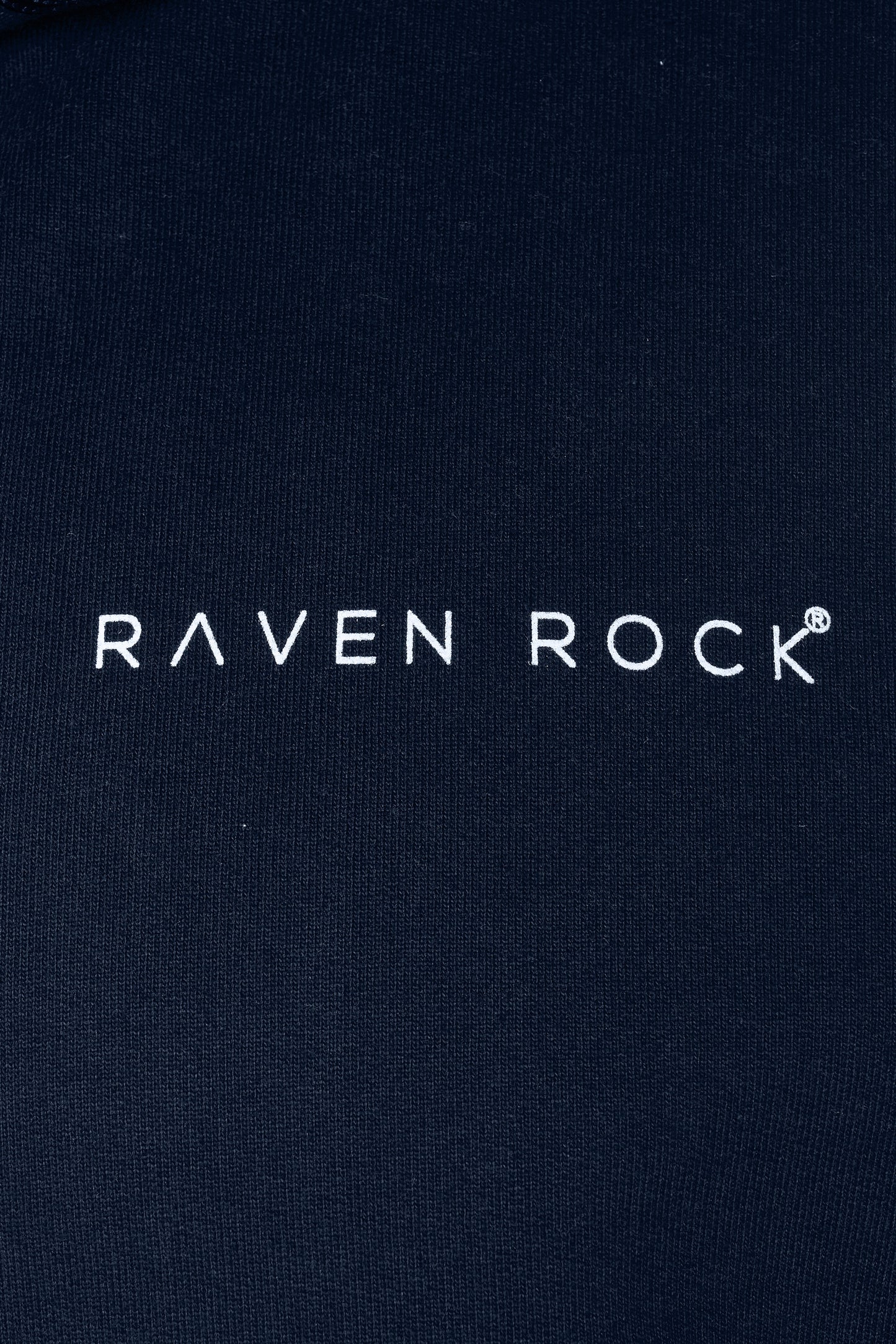 Close-up of RAVEN ROCK chest logo on navy hoodie – made in the UK from traceable cotton