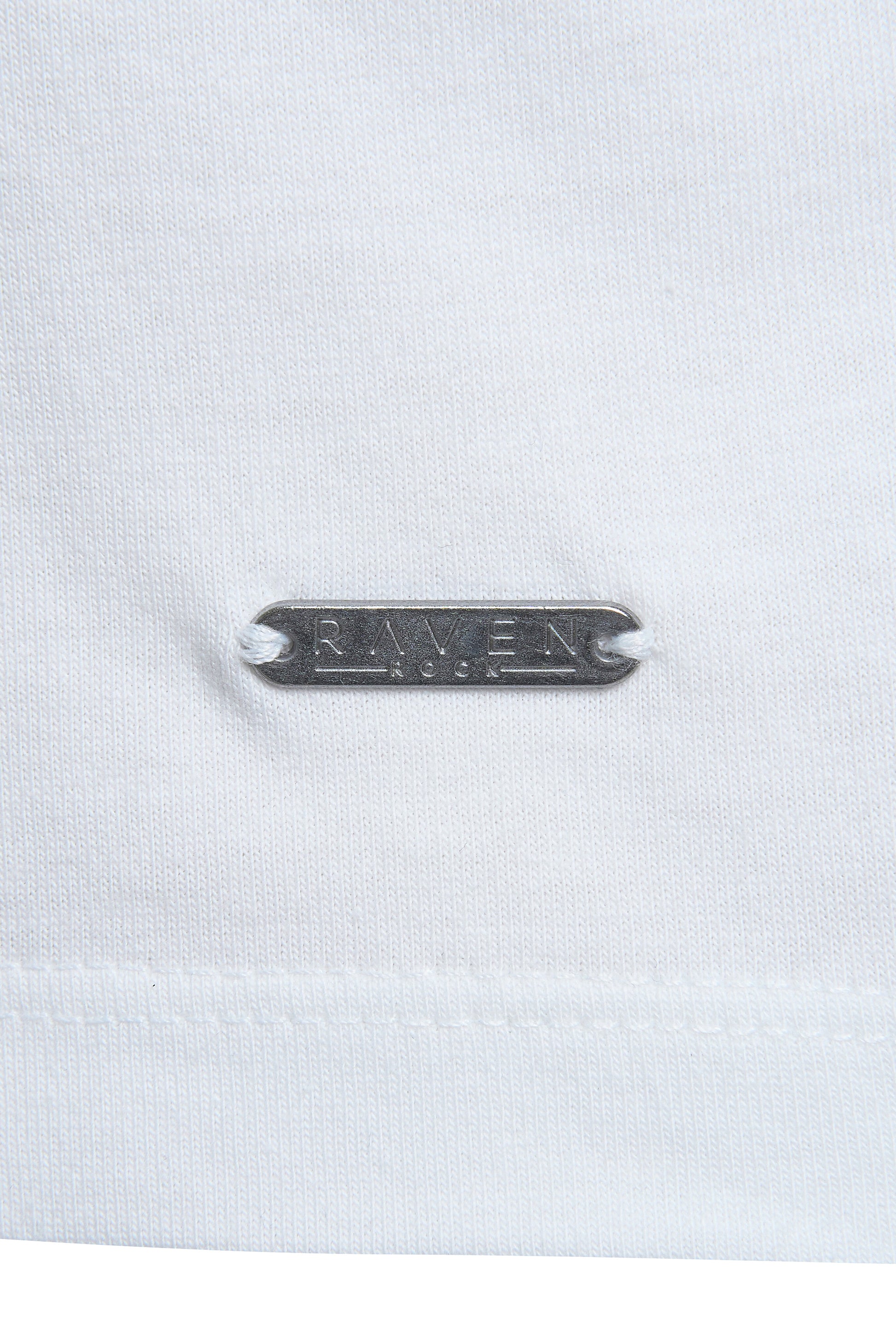 Close-up of branded metal tag stitched on white t-shirt