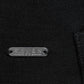 Close-up of a black garment with a branded metal label on a black hoodie
