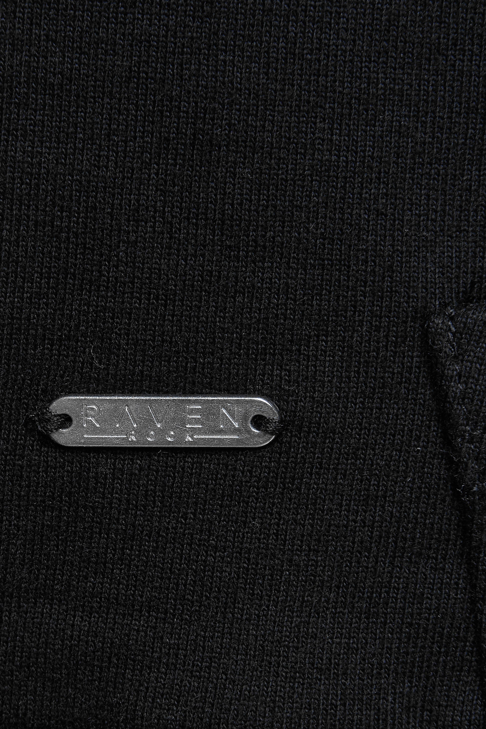 Close-up of a black garment with a branded metal label on a black hoodie