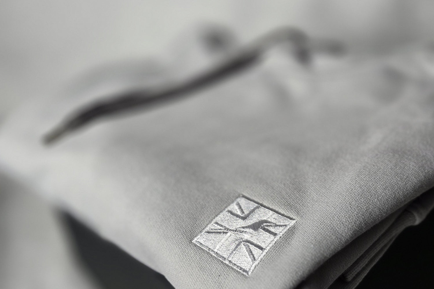 Grey hoodie with a logo on a blurred background