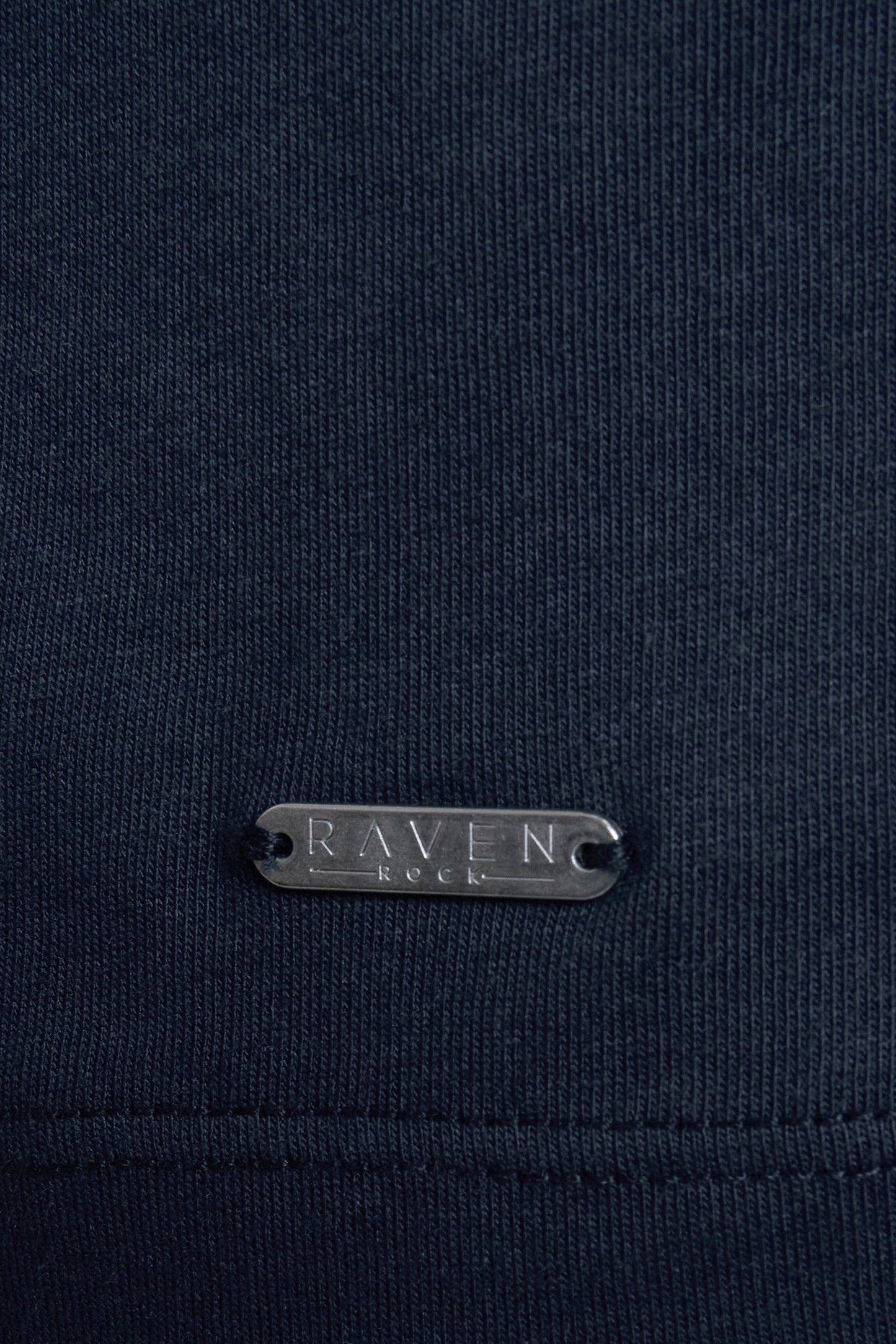 Navy blue fabric with a RAVEN ROCK metal tag
