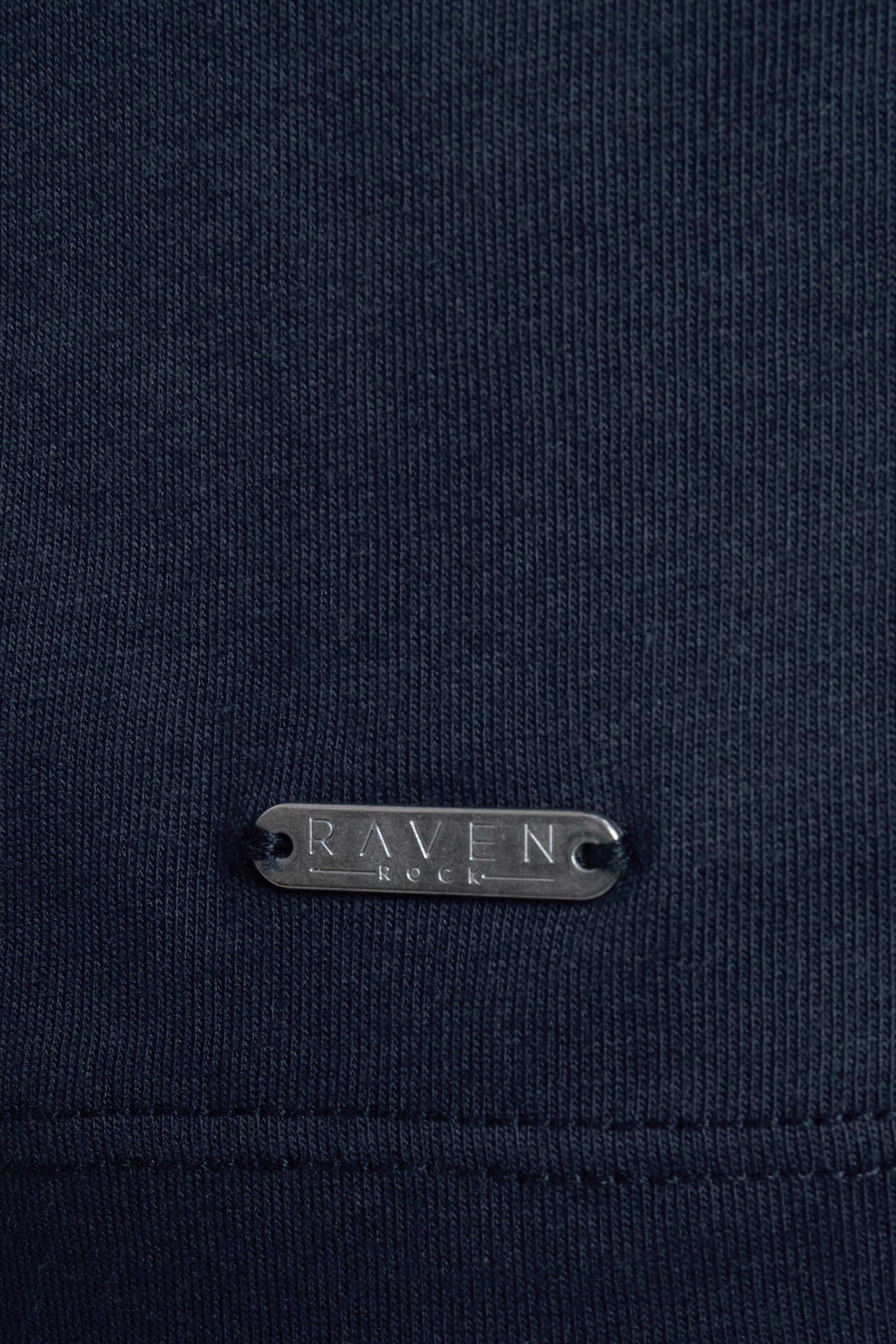 Navy blue fabric with a RAVEN ROCK metal tag