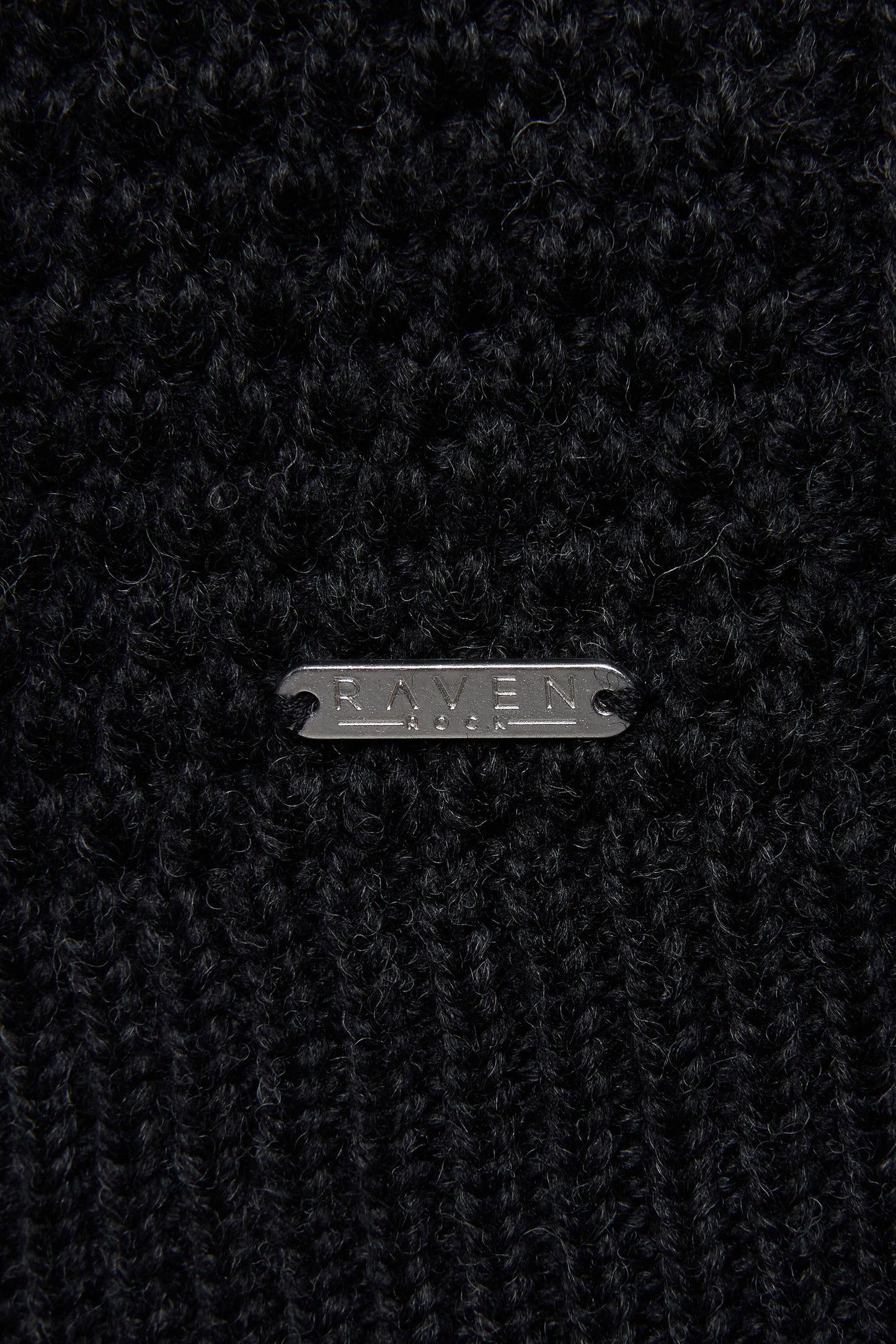 Close-up of a black wool yarn with RAVEN ROCK metal tag 