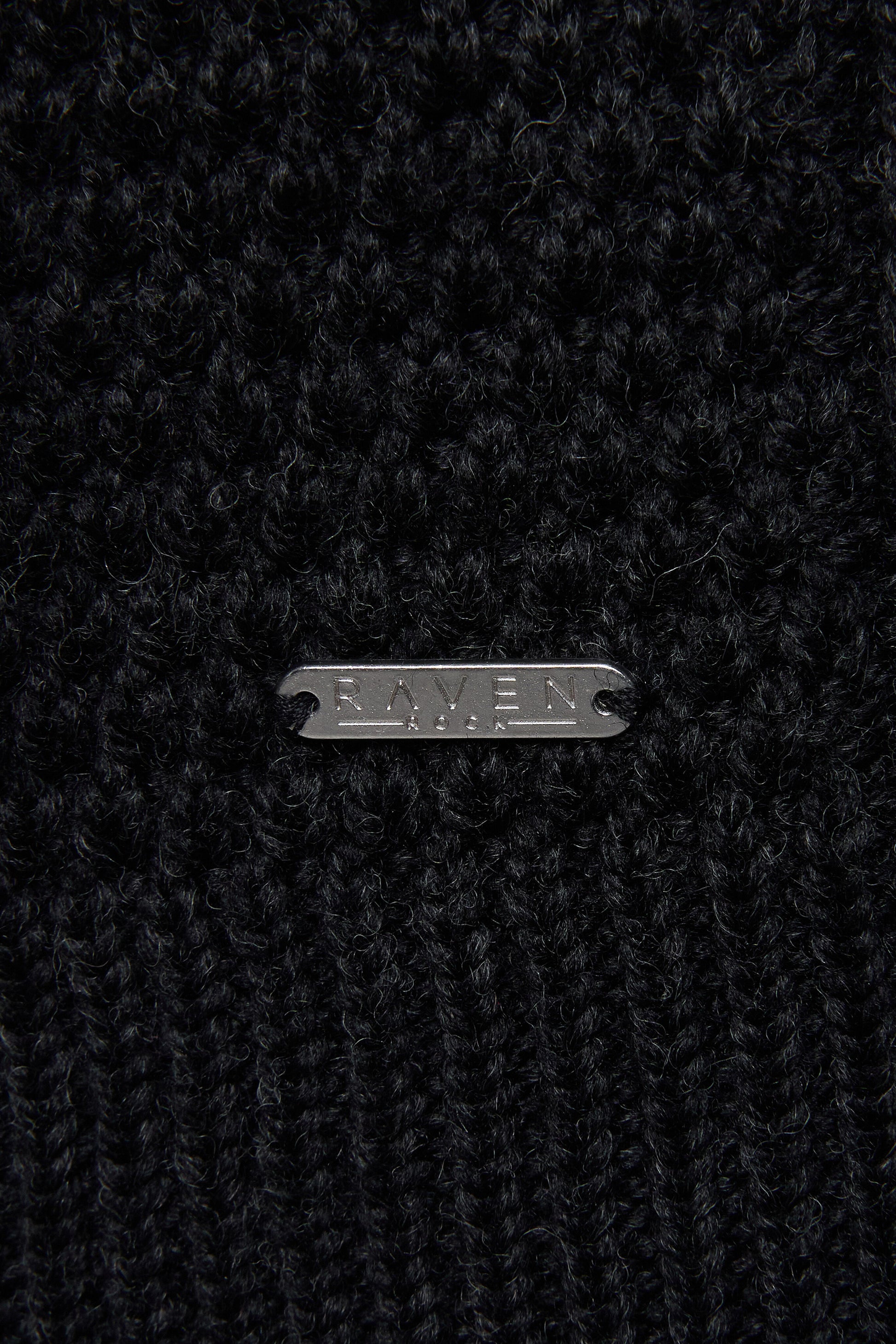 Close-up of a black wool yarn with RAVEN ROCK metal tag 